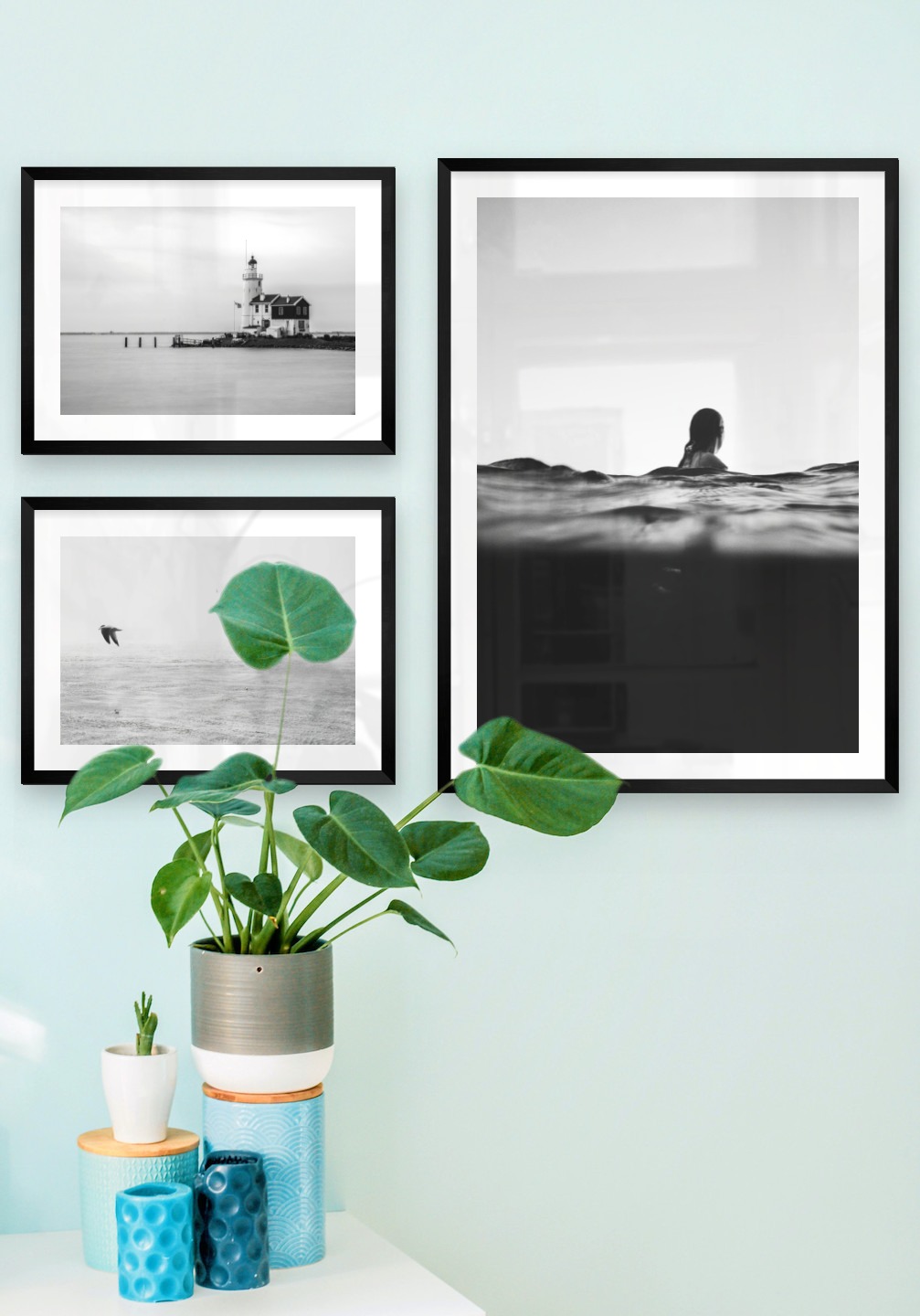 Gallery wall with picture frames in black in sizes 30x40 and 50x70 with prints "Pier with building", "Birds over the sea" and "Person in the water"