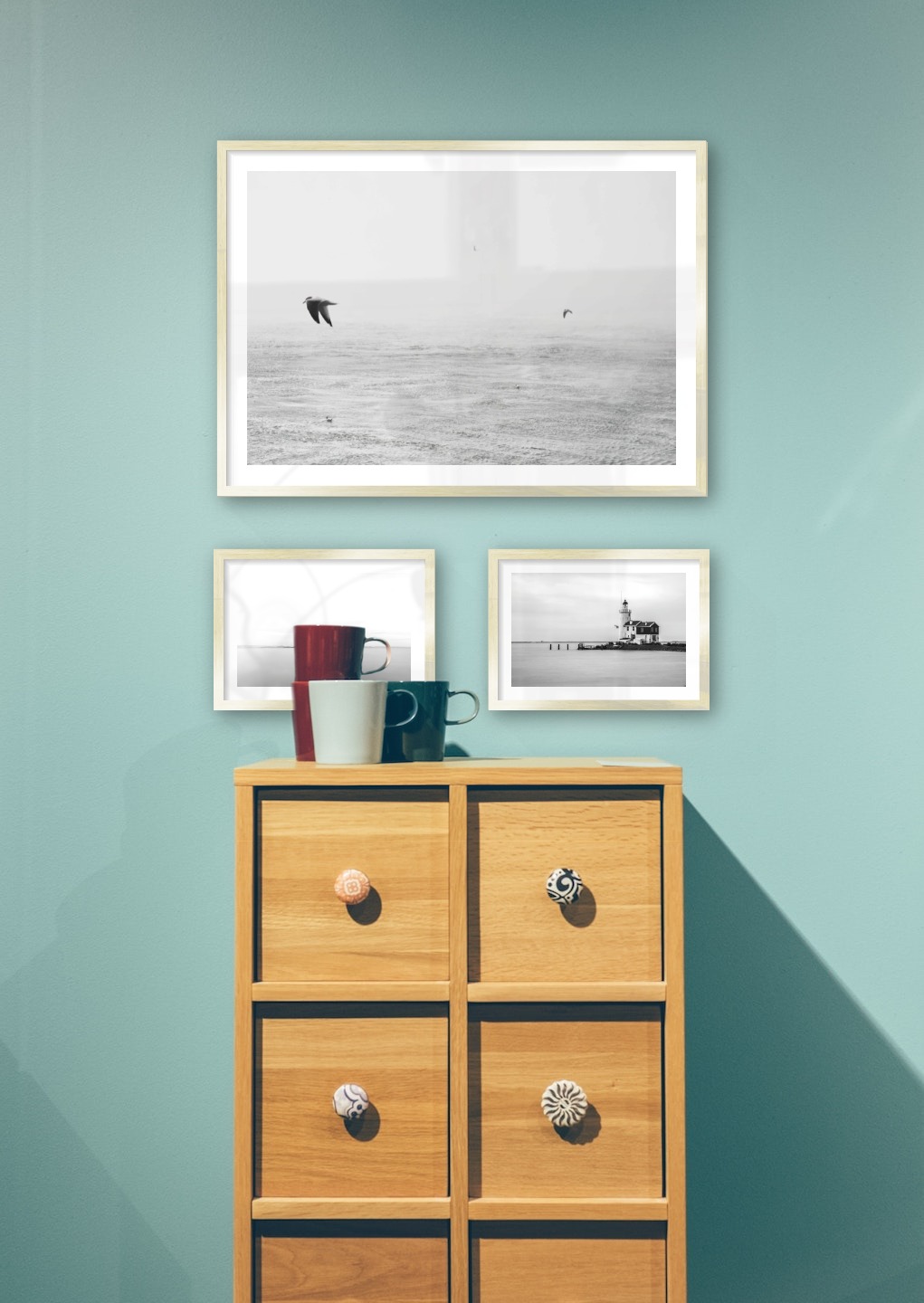 Gallery wall with picture frames in gold in sizes 50x70 and 21x30 with prints "Birds over the sea", "Pillars in the water" and "Pier with building"