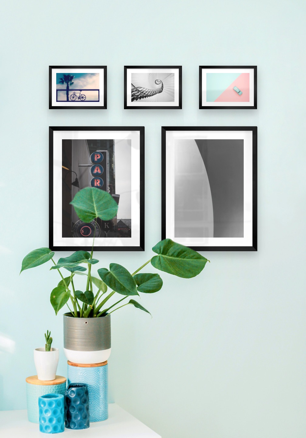 Gallery wall with picture frames in black in sizes 30x40 and 13x18 with prints "Sign "Park"", "Line", "Bicycle in front of sky", "Circular stair railing" and "Blue car and pink"