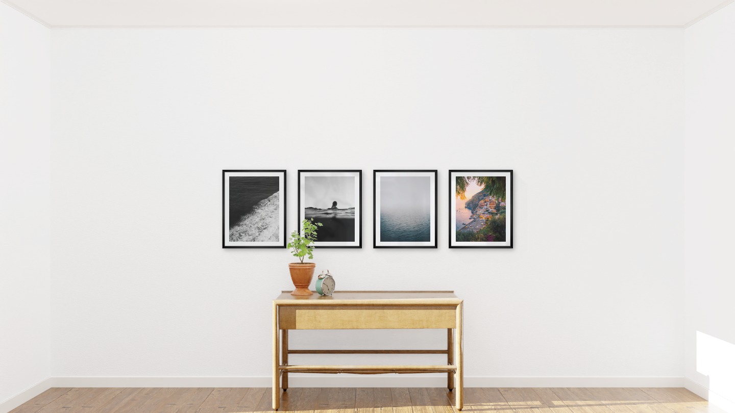Gallery wall with picture frames in black in sizes 40x50 with prints "Swell from waves", "Person in the water", "Fog over the sea" and "City by the sea"