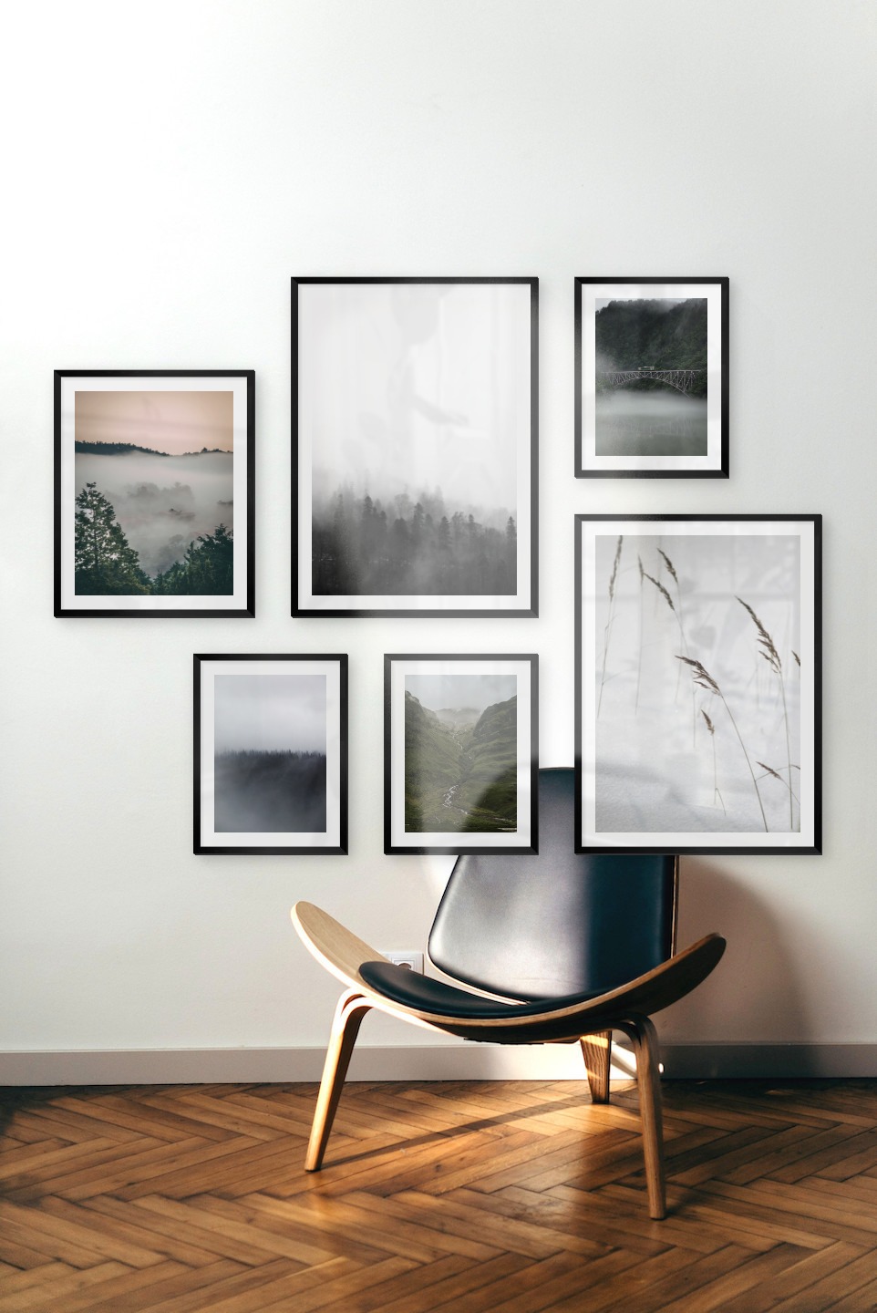 Gallery wall with picture frames in black in sizes 40x50, 50x70 and 30x40 with prints "Wooden tops and orange sky", "Foggy wooden tops", "Fog over treetops", "Stream in valley", "Sharp in the snow" and "Train over bridge"