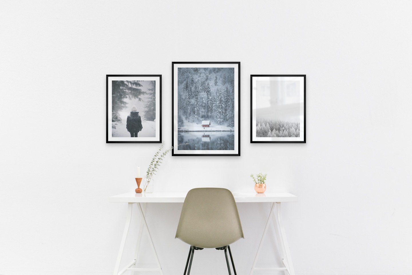 Gallery wall with picture frames in black in sizes 40x50 and 50x70 with prints "Person in the snow", "Cottage by the lake" and "Wooden tops in winter"