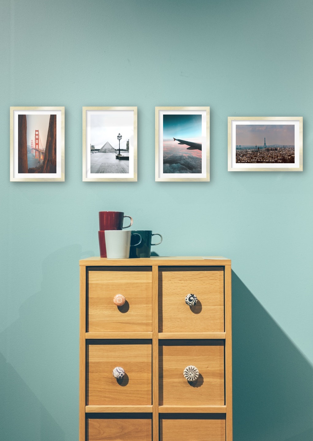 Gallery wall with picture frames in gold in sizes 21x30 with prints "Golden Gate Bridge", "Louvre in Paris", "Above the clouds" and "Eifel Tower in Paris"