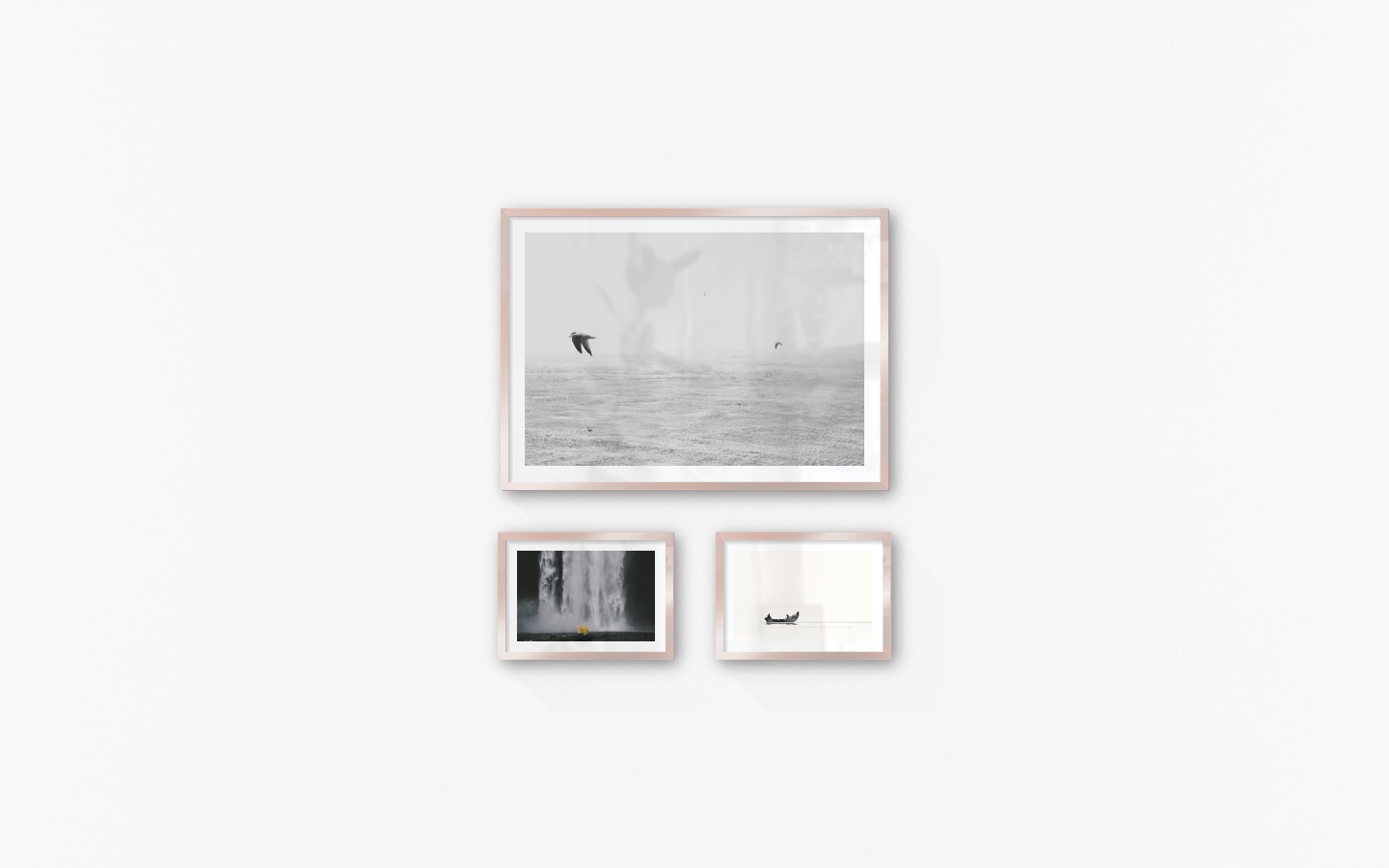 Gallery wall with picture frames in copper in sizes 50x70 and 21x30 with prints "Birds over the sea", "Waterfall with people" and "People in boat"