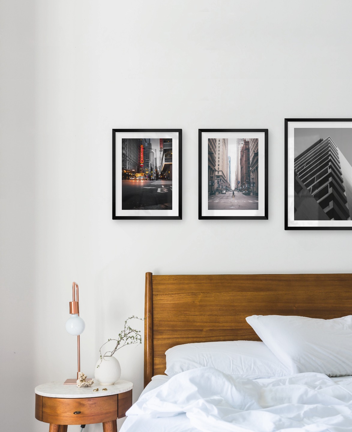 Gallery wall with picture frames in black in sizes 30x40 and 40x50 with prints "Busy city center", "Man walking across the street" and "Black and white building"