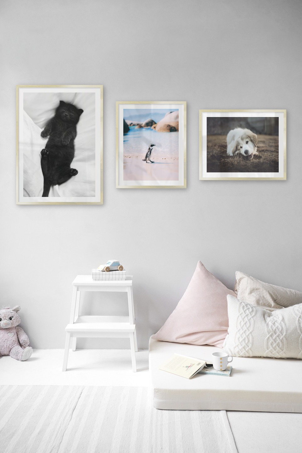 Gallery wall with picture frames in gold in sizes 50x70 and 40x50 with prints "Cat in bed", "Penguin on the beach" and "Dog chewing"