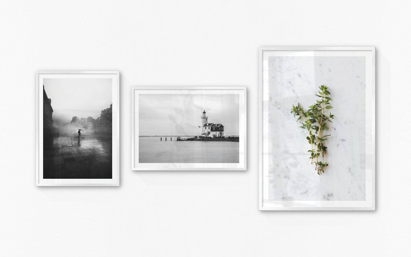 Gallery wall with picture frames in silver in sizes 50x70 and 70x100 with prints "Rainy city", "Pier with building" and "Herbs"