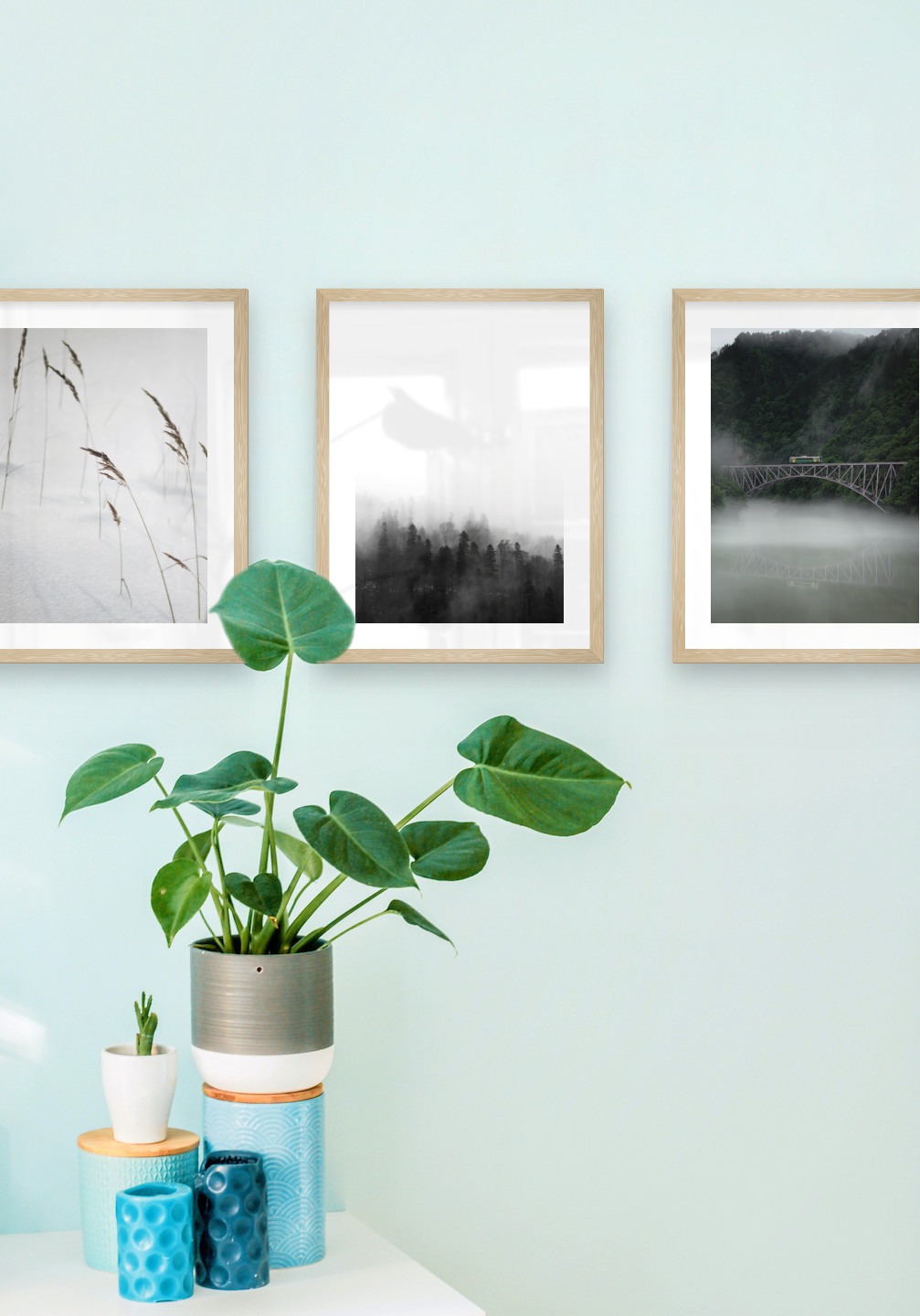 Gallery wall with picture frames in wood in sizes 30x40 with prints "Sharp in the snow", "Foggy wooden tops" and "Train over bridge"