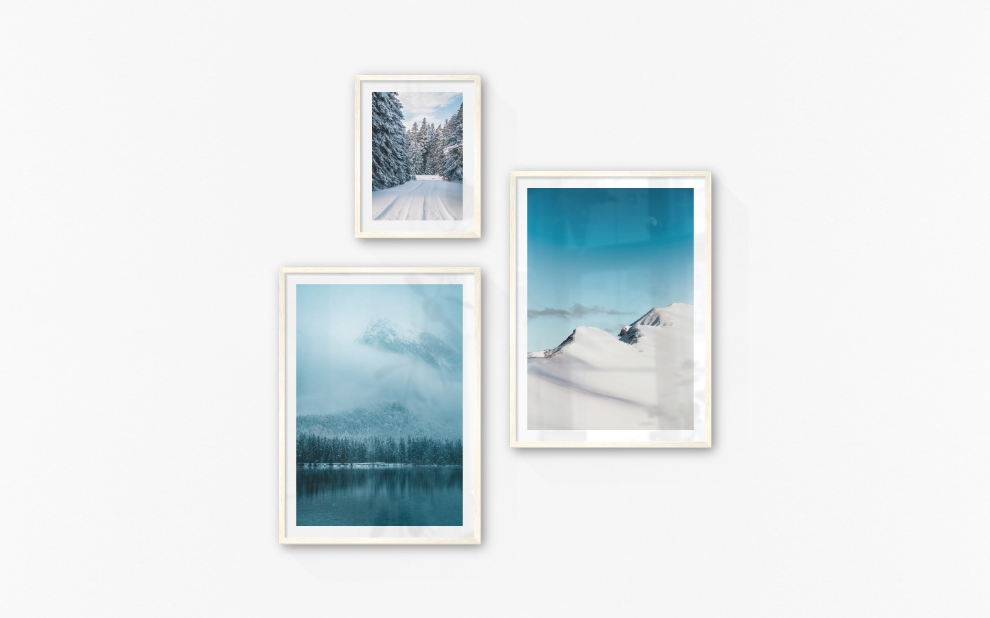 Gallery wall with picture frames in light wood in sizes 30x40 and 50x70 with prints "Snowy road", "Lake, mountains and forest" and "Snowy mountain peaks"