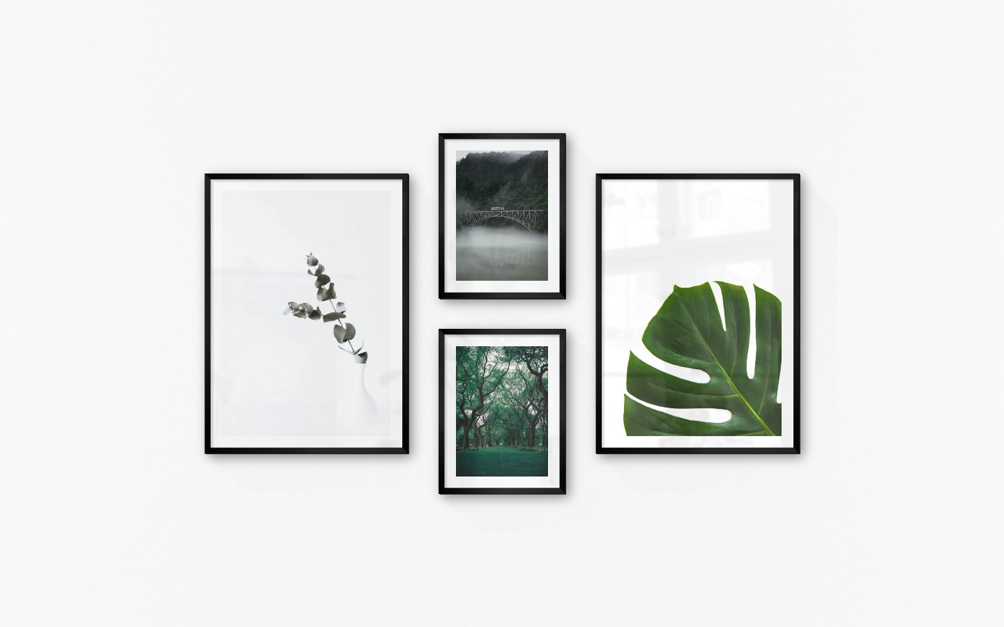 Gallery wall with picture frames in black in sizes 50x70 and 30x40 with prints "Branch in vase", "Train over bridge", "Greenery and trees" and "Plant"