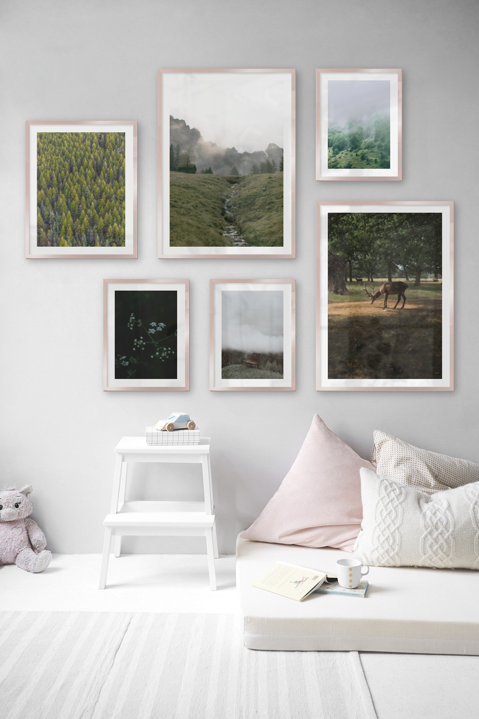 Gallery wall with picture frames in copper in sizes 40x50, 50x70 and 30x40 with prints "Trees from above", "Green valley in front of mountains", "Green plant", "Bench in misty nature", "Deer in forest" and "Slope with trees"