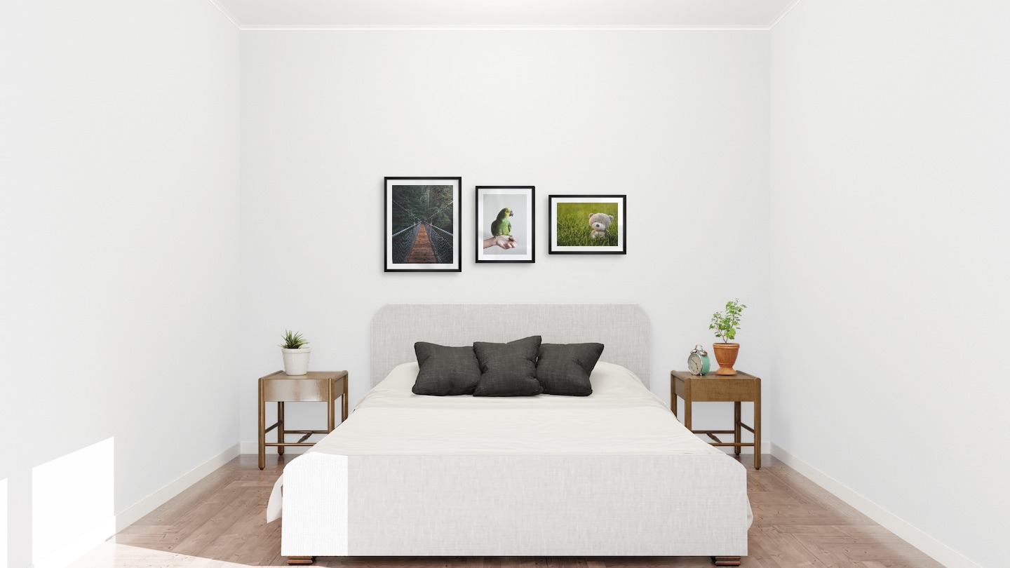 Gallery wall with picture frames in black in sizes 40x50 and 30x40 with prints "Bridge in the woods", "Green parrot" and "Teddy bear in a field"