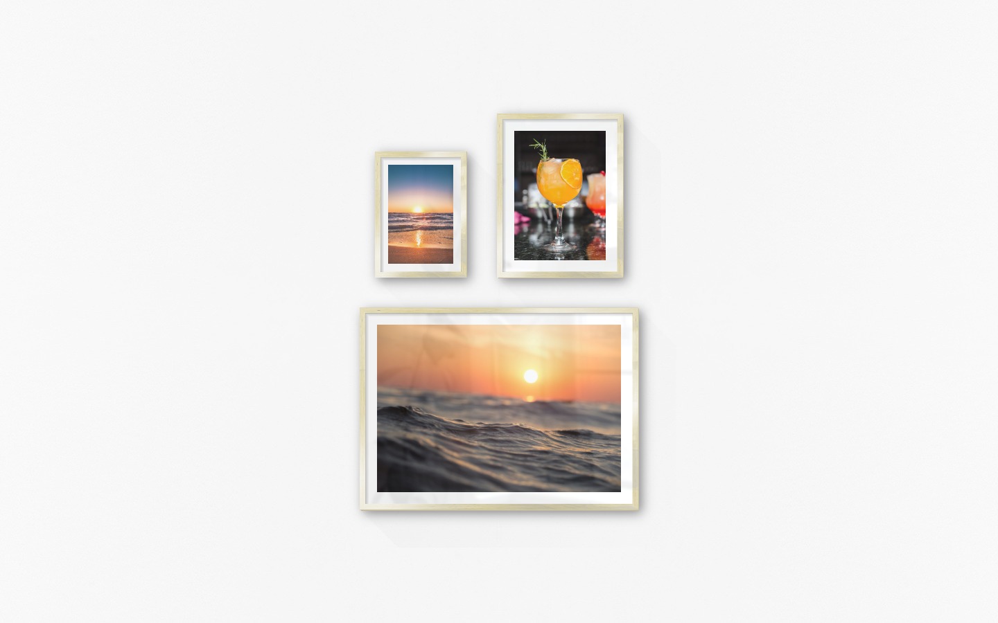 Gallery wall with picture frames in gold in sizes 21x30, 30x40 and 50x70 with prints "Sunset", "High orange drink" and "Waves and the sun"
