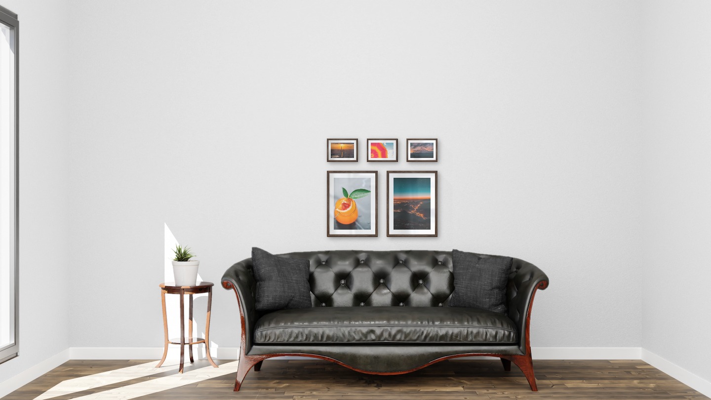 Gallery wall with picture frames in dark wood in sizes 30x40 and 13x18 with prints "Orange drink", "City lights on mountains", "Skyline at sunset", "Parasol and sky" and "Sunset and mountains"