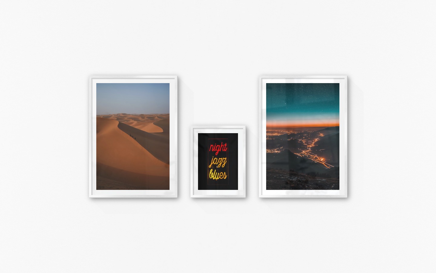 Gallery wall with picture frames in silver in sizes 50x70 and 30x40 with prints "Desert", "Neon signs" and "City lights on mountains"
