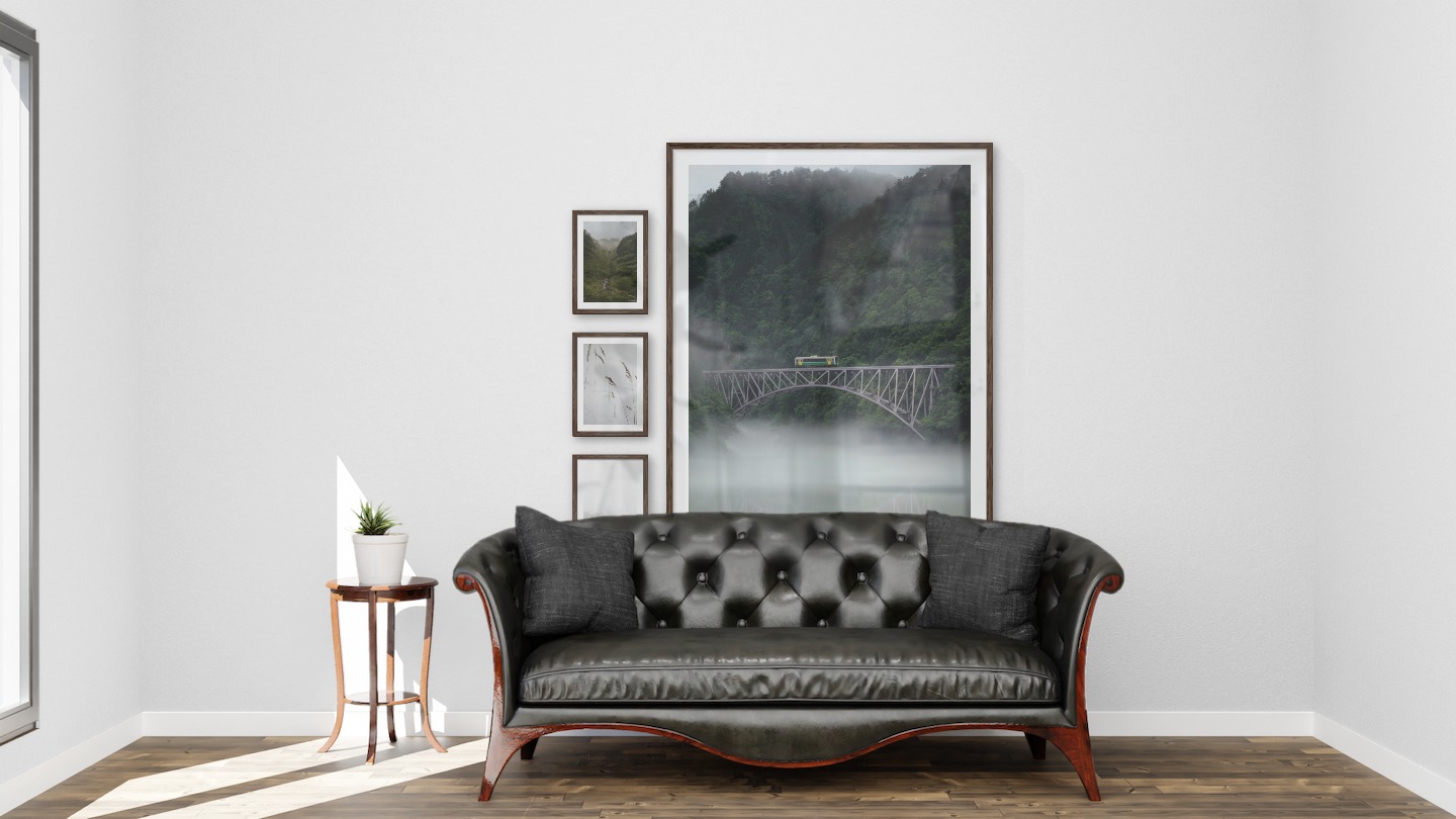 Gallery wall with picture frames in dark wood in sizes 21x30 and 100x150 with prints "Stream in valley", "Sharp in the snow", "Foggy wooden tops" and "Train over bridge"