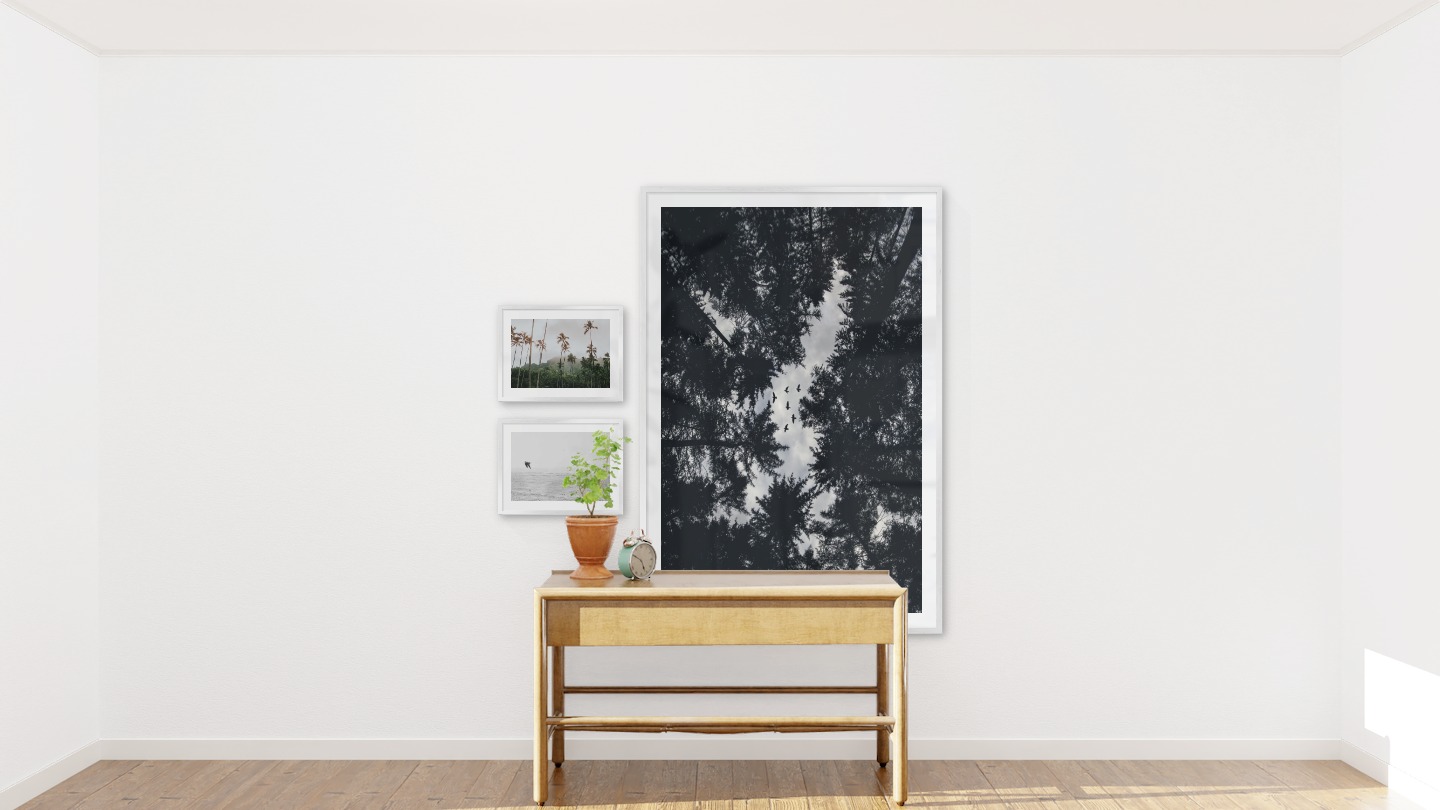 Gallery wall with picture frames in silver in sizes 30x40 and 100x150 with prints "Palm trees and mountains", "Birds over the sea" and "Wooden tops and birds"