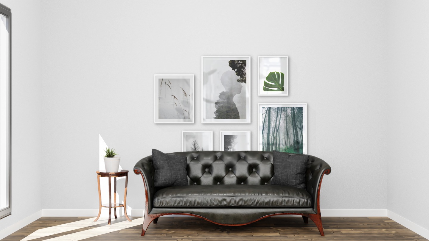 Gallery wall with picture frames in white in sizes 40x50, 50x70 and 30x40 with prints "Sharp in the snow", "Silhouette and tree", "Trees in the snow", "Foggy wooden tops from the side", "Tall trees" and "Plant"