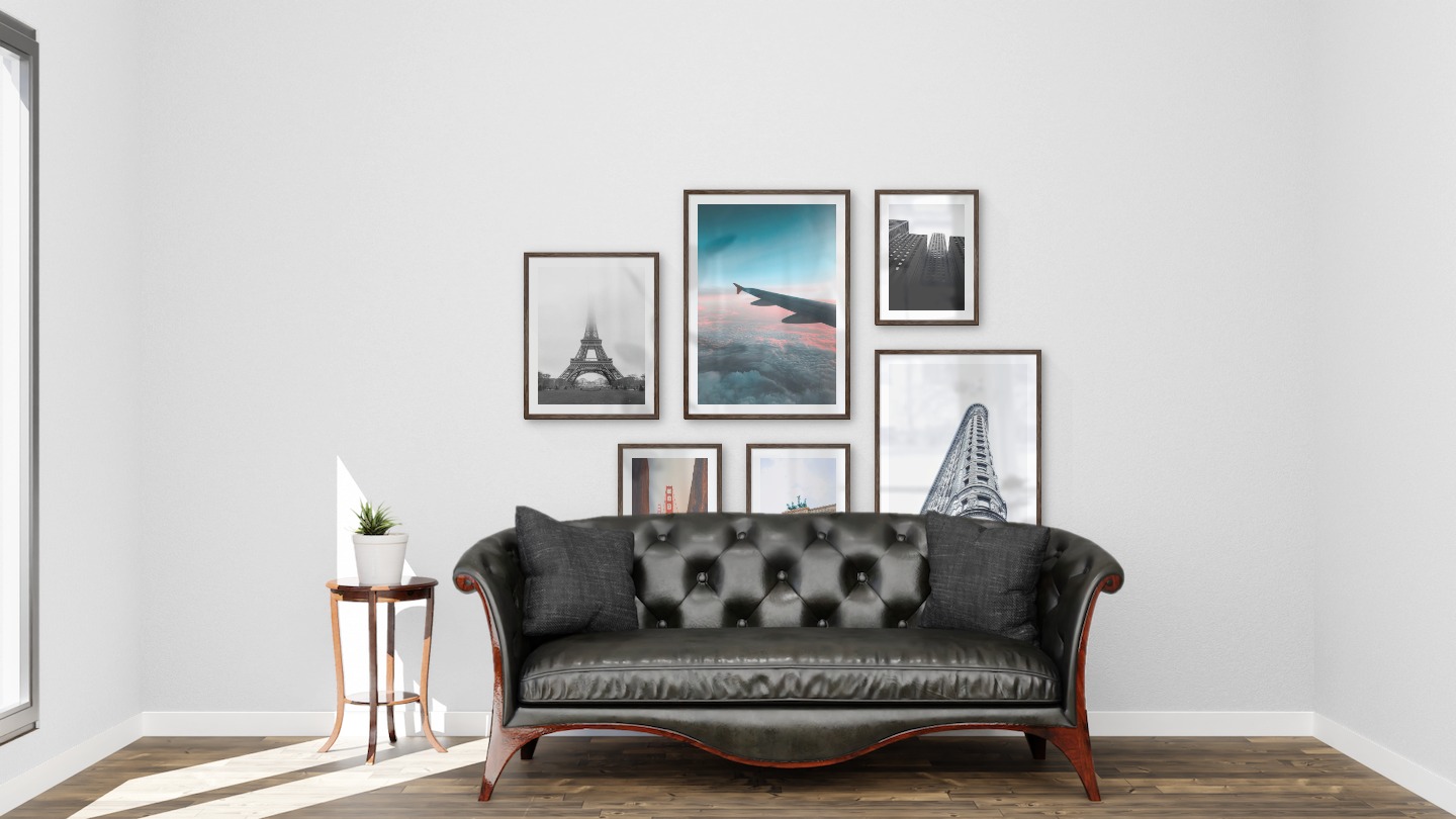 Gallery wall with picture frames in dark wood in sizes 40x50, 50x70 and 30x40 with prints "Eifel tower with fog", "Above the clouds", "Golden Gate Bridge", "Berlin", "Gray building" and "High buildings"