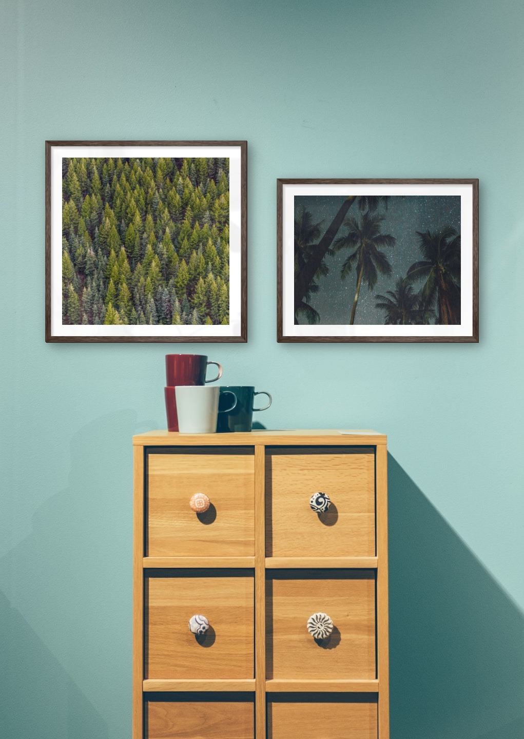 Gallery wall with picture frames in dark wood in sizes 50x50 and 40x50 with prints "Trees from above" and "Palm trees and night sky"