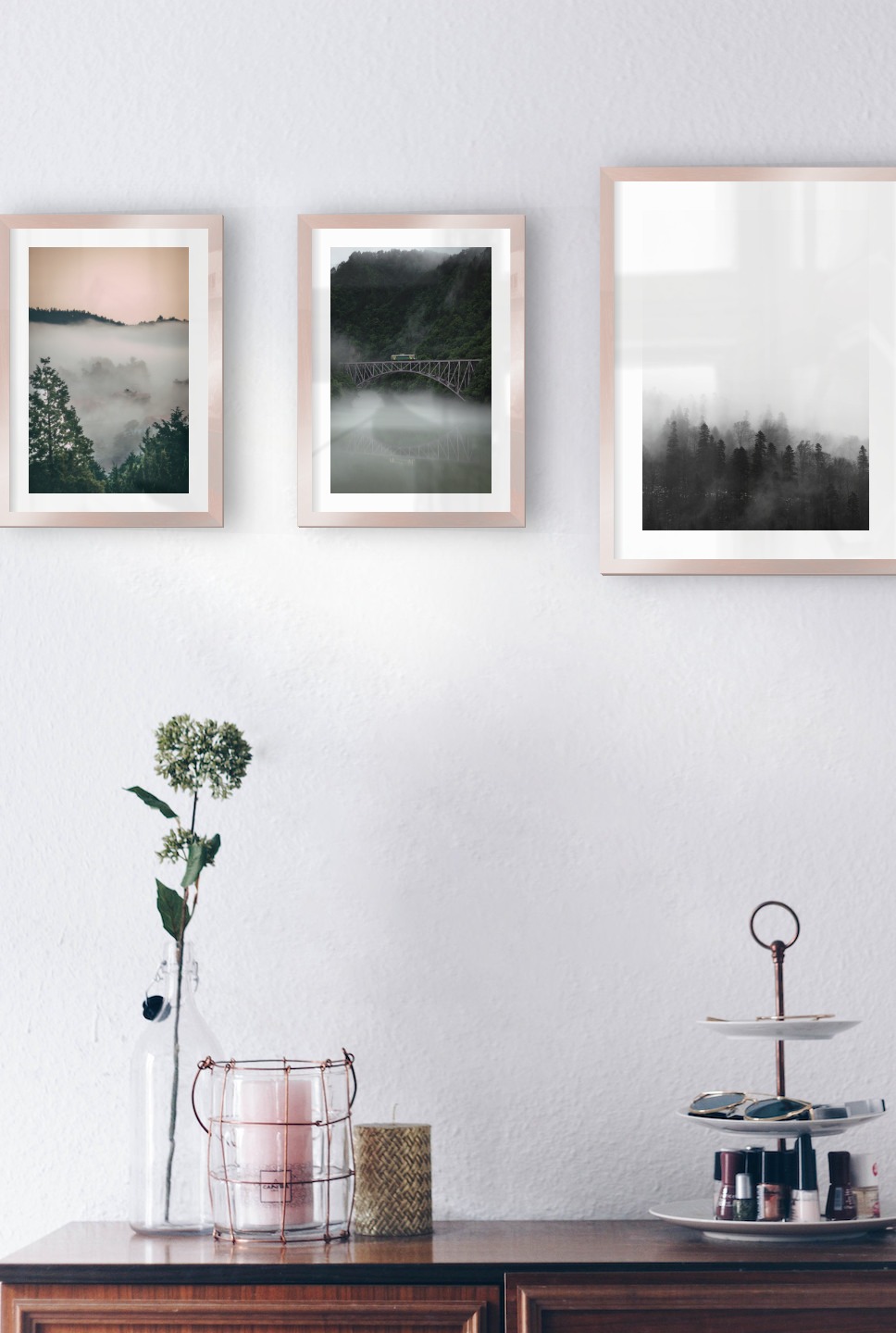 Gallery wall with picture frames in copper in sizes 21x30 and 30x40 with prints "Wooden tops and orange sky", "Train over bridge" and "Foggy wooden tops"