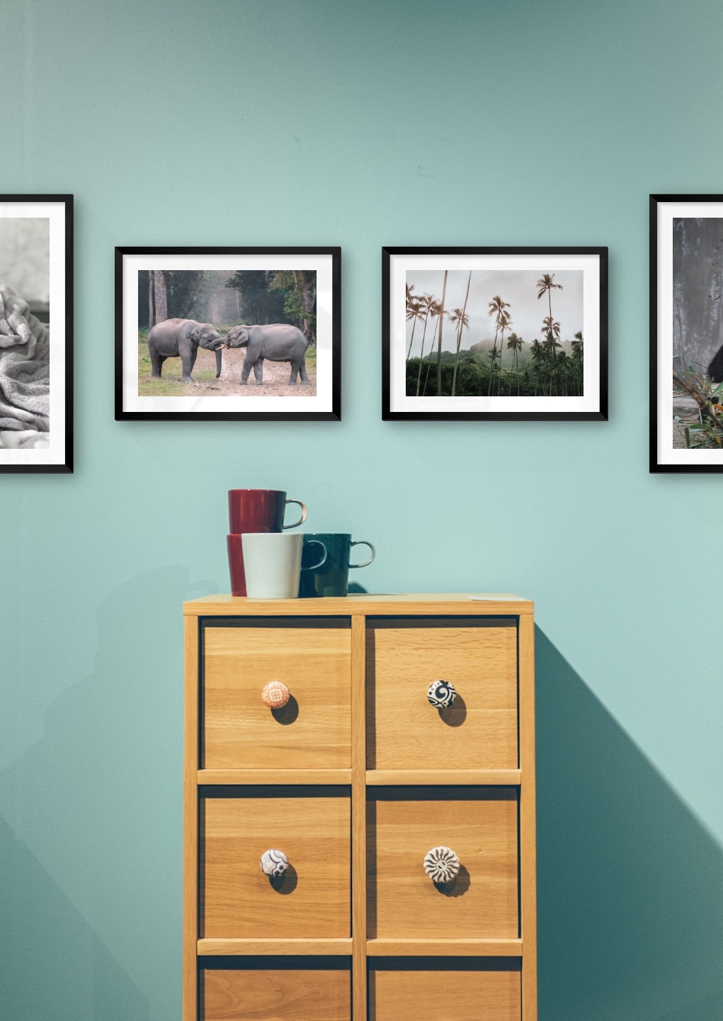 Gallery wall with picture frames in black in sizes 40x50 and 30x40 with prints "Cat in felt", "Elephants", "Palm trees and mountains" and "Panda"