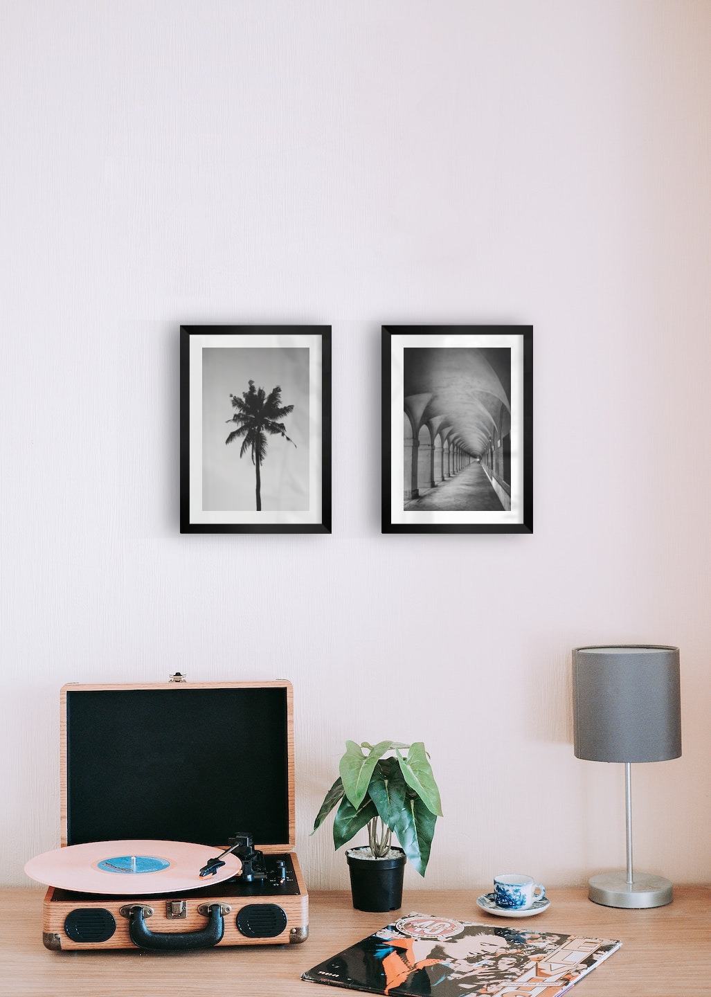 Gallery wall with picture frames in black in sizes 21x30 with prints "Palm" and "Hallway with pillars and arches"